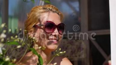 在阳光明媚的花圃里，夏天戴太阳镜的快乐女人